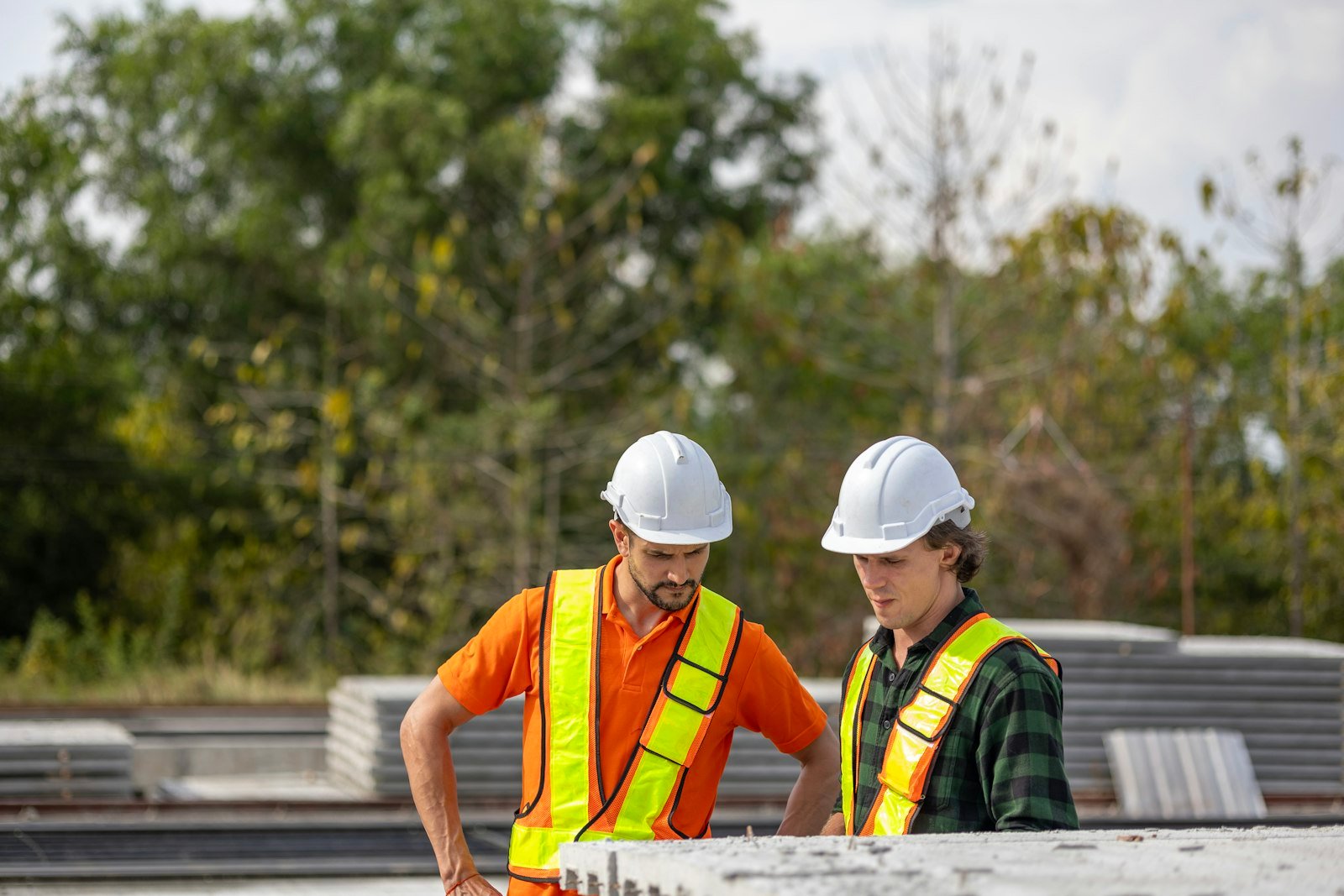 Técnicos com capacete e colete de segurança inspecionando estrutura em obra
