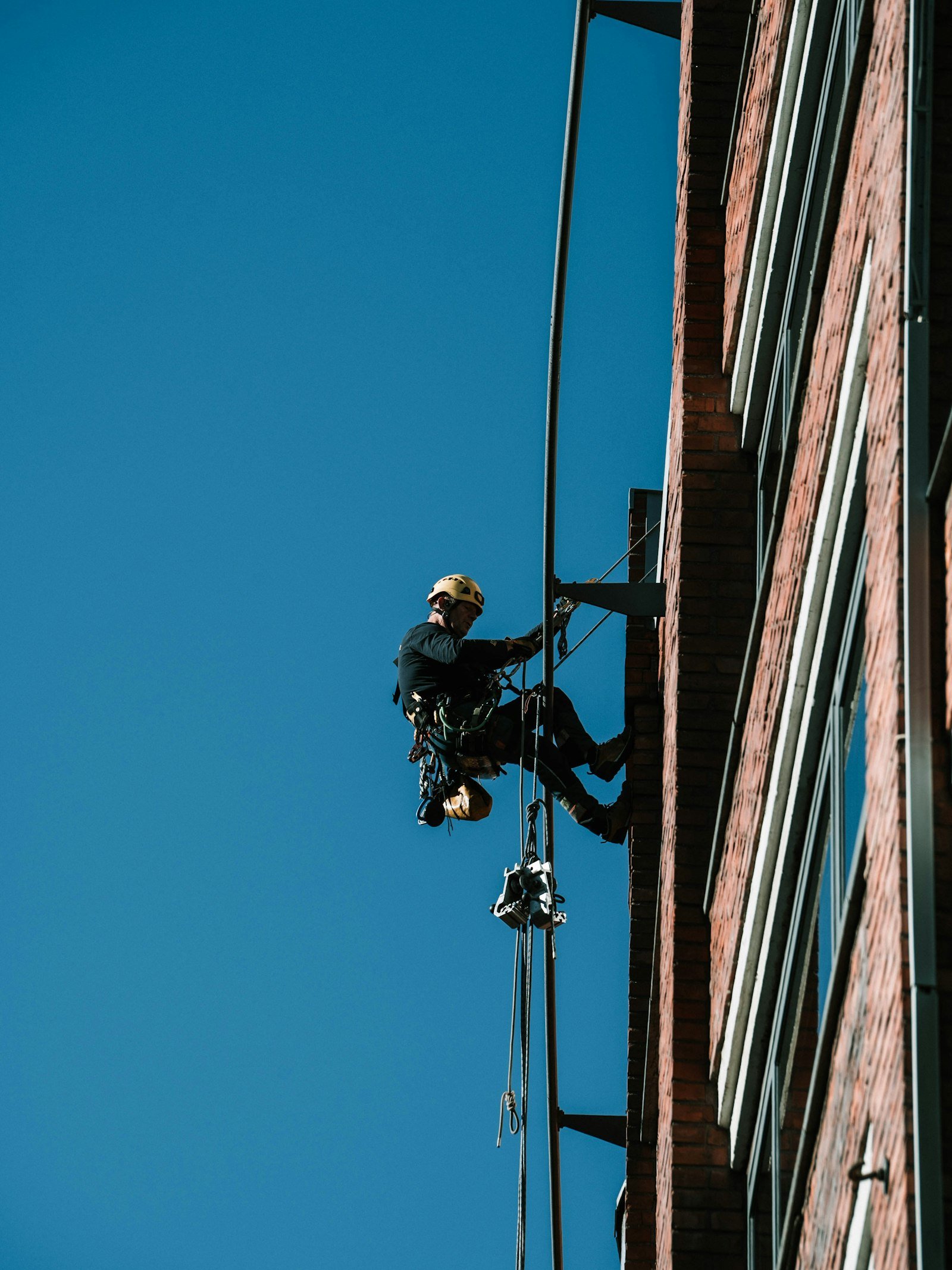 Técnico em acesso por corda realizando reparo em fachada predial